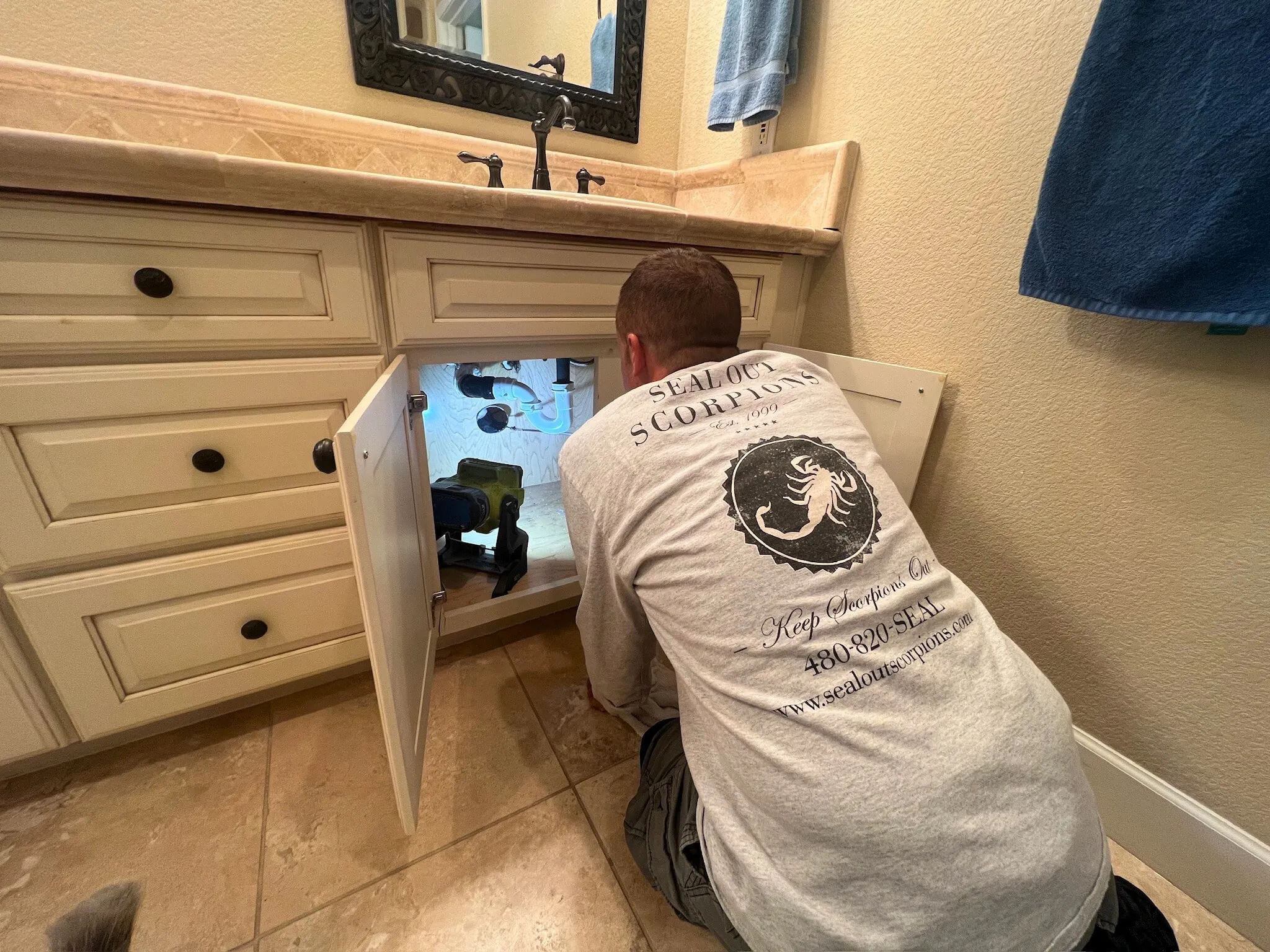 Technician applying an under sink seal to block potential pest entry points.